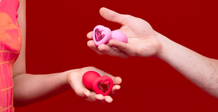 2 Vibrating Heart Anal-Plugs in den Händen einer Frau und eines Mannes